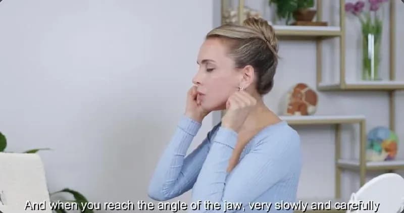 A frame from a real lesson, a trainer demonstrating a jaw massage technique